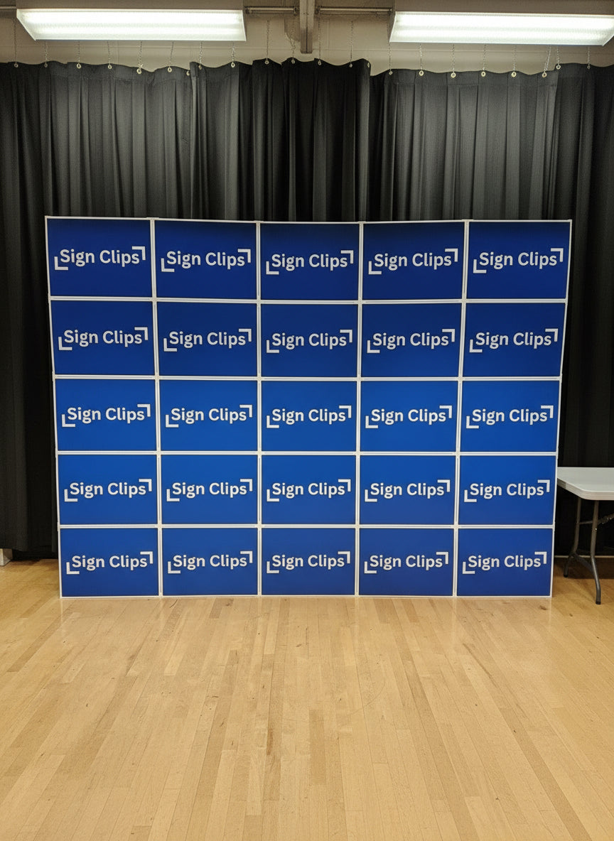 A series of blue yard signs arranged in a wall backdrop formation, set against a black backdrop.